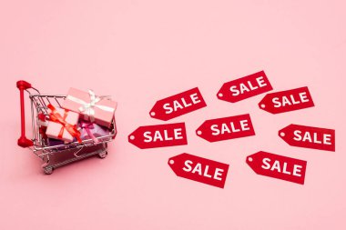 Oyuncak alışveriş arabasının en üst görüntüsü, etiketlerin yanında pembe, siyah cuma konsepti üzerine yazılar var. 