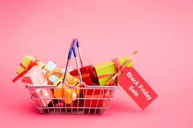Hediyeli alışveriş sepeti ve üzerinde pembe, siyah cuma konsepti olan kırmızı etiket. 