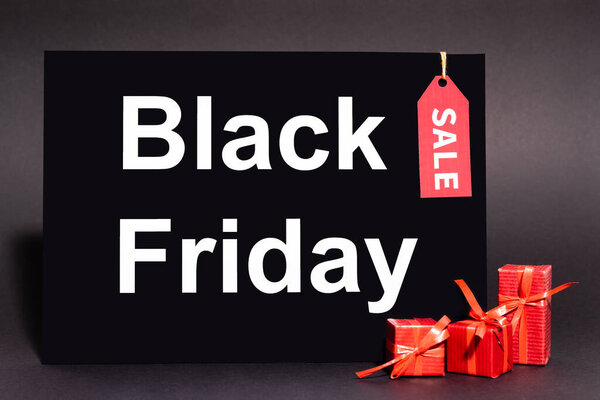 placard with black friday lettering and sale tag near presents on dark background