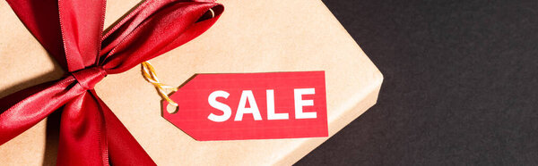 вид на подарочную коробку с лентой и биркой на темном фоне, черная пятница концепции, панорамный урожай