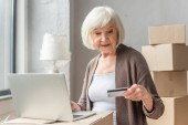 senior žena dělat on-line nákup s kreditní kartou a notebookem