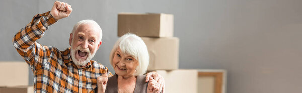 panoramic shot of excited senior couple with fists up showing hooray sign, moving concept
