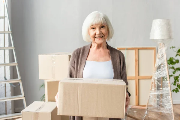 Alegre Anciana Sosteniendo Caja Cartón Mirando Cámara Concepto Movimiento — Foto de Stock