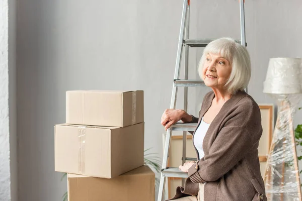 Sonriente Mujer Mayor Sentada Escalera Mirando Hacia Otro Lado Con — Foto de Stock