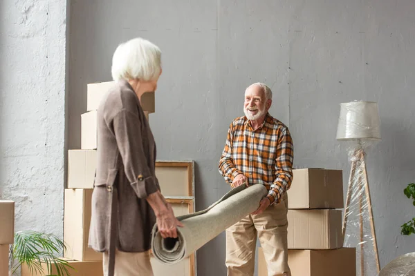 Glimlachend Senior Paar Rollend Tapijt Nieuw Huis Bewegend Concept — Stockfoto