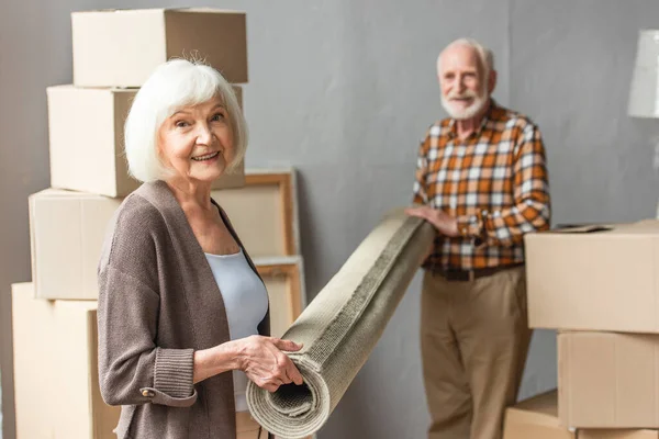 Glimlachend Senior Paar Rollend Tapijt Nieuw Huis Bewegend Concept — Stockfoto