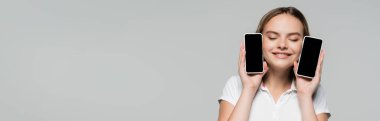 Gri, siyah cuma konseptine izole edilmiş boş ekranlı akıllı telefonları tutan neşeli kadın konsepti 