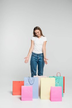 Gri, siyah cuma günündeki alışveriş çantalarını gösteren neşeli bir kadın. 