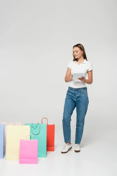 Joyful Woman Standing Holding Digital Tablet Shopping Bags Grey Black — Stock Photo, Image