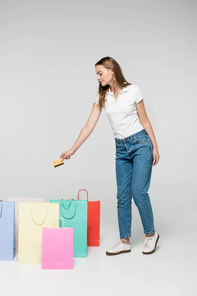 Mujer Joven Sosteniendo Tarjeta Crédito Cerca Bolsas Compras Gris Concepto — Foto de Stock
