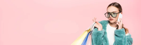 穿着太阳镜 拿着用粉色黑色星期五概念隔开的购物袋在智能手机上聊天的时髦女人的全景系列 — 图库照片