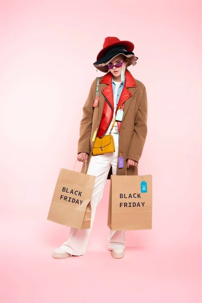 戴着太阳镜 头戴销售标签 戴着粉色黑色星期五概念购物袋的年轻女性 — 图库照片