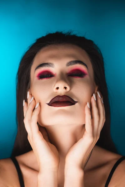 Młoda Kobieta Ciemnym Makijażem Zamkniętymi Oczami Dotykająca Niebieskiej Twarzy — Zdjęcie stockowe