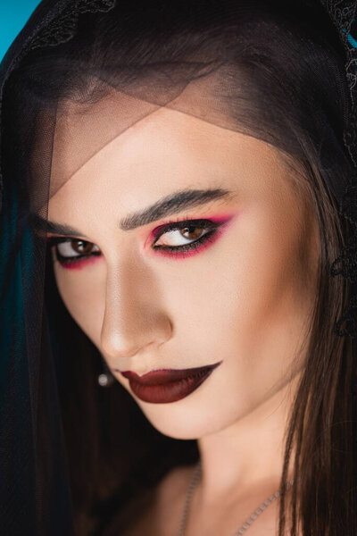 close up of evil bride with black makeup and veil looking at camera 