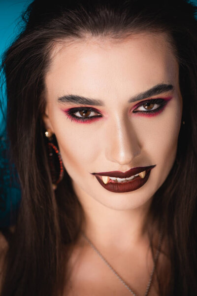 vampire with black makeup and white scary teeth looking at camera 