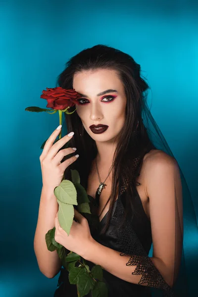 Młoda Kobieta Ciemnym Makijażu Gospodarstwa Czerwona Róża Niebiesko — Zdjęcie stockowe
