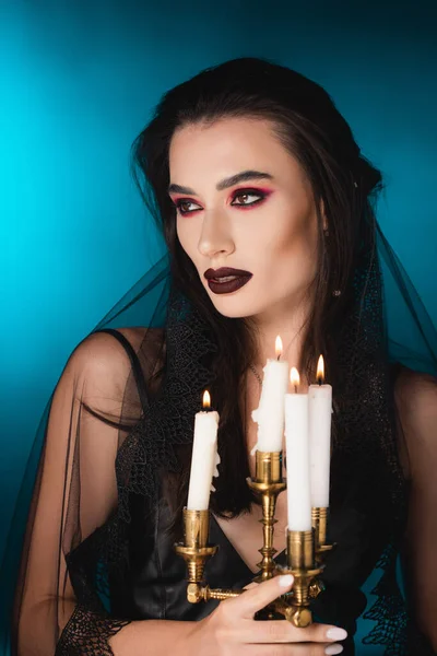 Pale Woman Black Makeup Looking Away Holding Burning Candles Blue — Stock Photo, Image