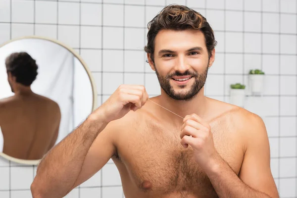 Banyoda Diş Ipi Tutarken Kameraya Gülümseyen Gömleksiz Bir Adam — Stok fotoğraf