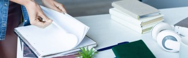 cropped view of woman turning pages of notebook, horizontal banner