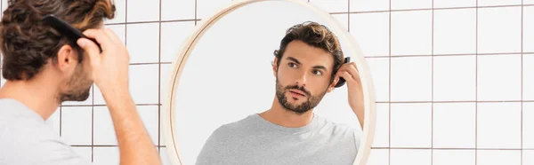 Young Man Combing Hair While Looking Mirror Blurred Foreground Bathroom — Stock Photo, Image