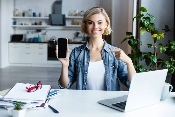 Mulher Sorridente Apontando Com Dedo Para Smartphone Com Tela Branco — Fotografia de Stock