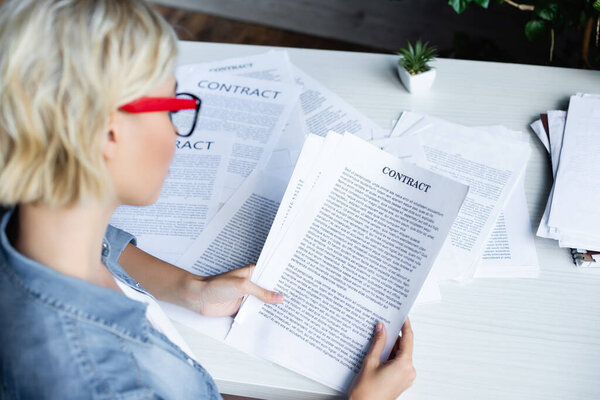 young blonde woman in eyeglasses working with documents