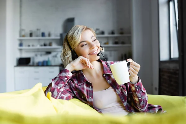 若いですブロンド女性のヘッドフォン飲料茶 — ストック写真