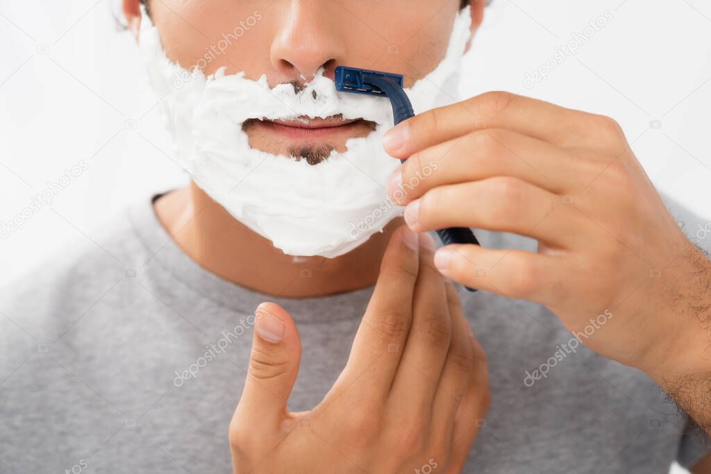 Cropped view of man holding razor while shaving isolated on grey 