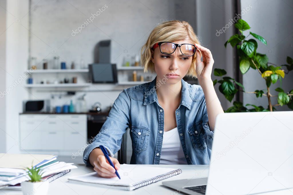 confused blonde woman making notes in notebook