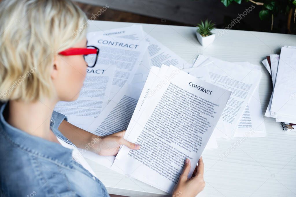 young blonde woman in eyeglasses working with documents