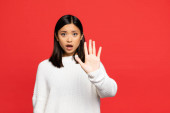 šokované asijské žena s otevřenými ústy ukazující stop znamení s dlaní izolované na červené 