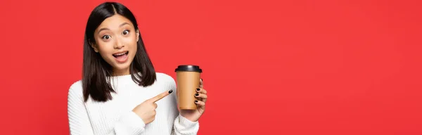 Збуджена Азіатська Жінка Вказує Пальцем Одноразову Чашку Ізольовано Червоному Банер — стокове фото