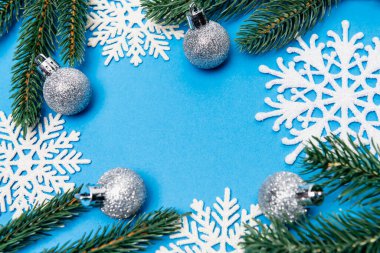 top view of snowflakes, silver baubles and spruce on blue background clipart