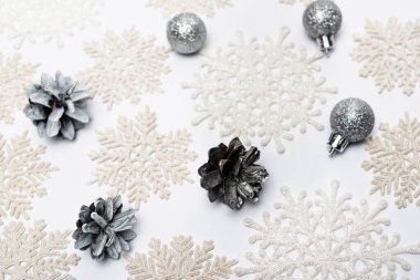 top view of snowflakes, silver baubles and cones on white background clipart