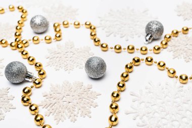 Beyaz arka planda kar taneleri olan gümüş ve altın Noel süslemeleri
