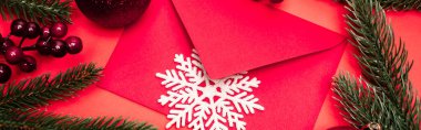 Kırmızı arkaplanda Noel süslemesi ve zarfının üst görünümü, afiş