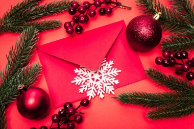 Kırmızı arkaplanda noel dekorasyonu ve zarf üst görünümü