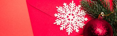 Kırmızı arkaplanda Noel süslemesi ve zarfının üst görünümü, afiş