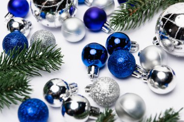 mavi, gümüş Noel süslemesi ve beyaz arkaplanda köknar dalları