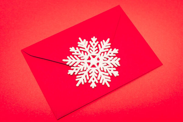 top view of snowflake and envelope on red background