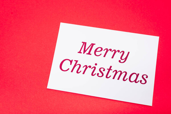 top view of white merry Christmas card on red background