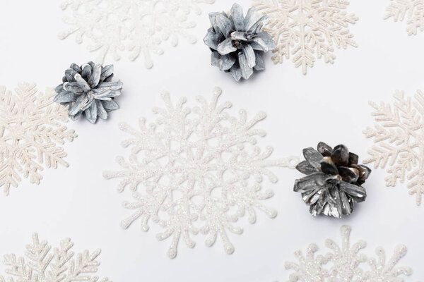 вид сверху на зимние снежинки и шишки на белом фоне
