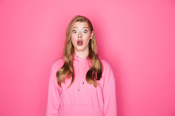 shocked beautiful woman with open mouth on pink background