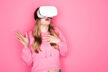Pembe arka planda VR kulaklık takmış güzel bir kadın.