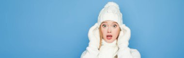 shocked beautiful woman in winter white outfit isolated on blue, banner clipart