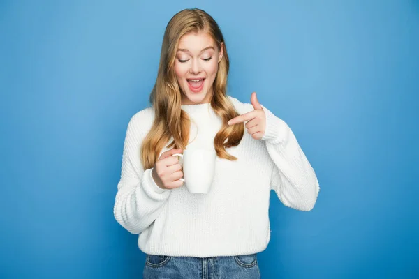 Happy Blonde Beautiful Woman Sweater Pointing Mug Isolated Blue Background — Stock Photo, Image
