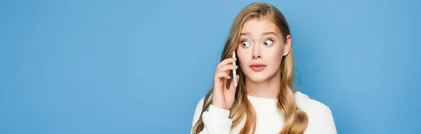 Surprised Blonde Beautiful Woman Sweater Talking Smartphone Isolated Blue Background — Stock Photo, Image