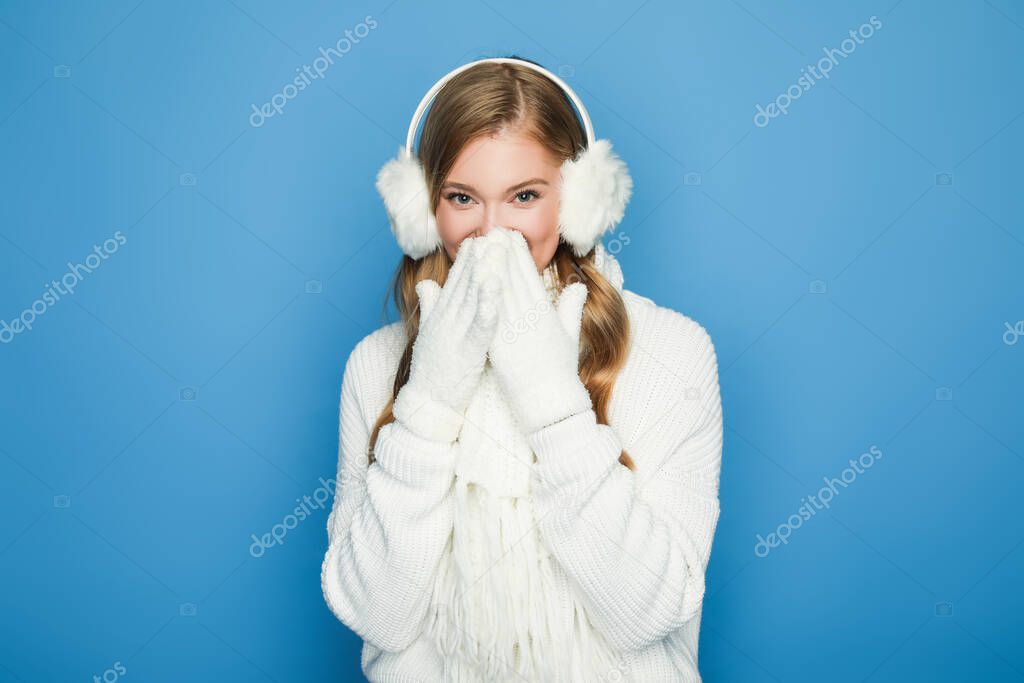 smiling beautiful woman in winter white outfit isolated on blue