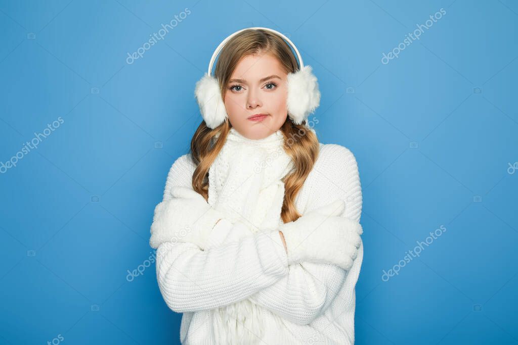 beautiful woman in winter white outfit feeling cold isolated on blue