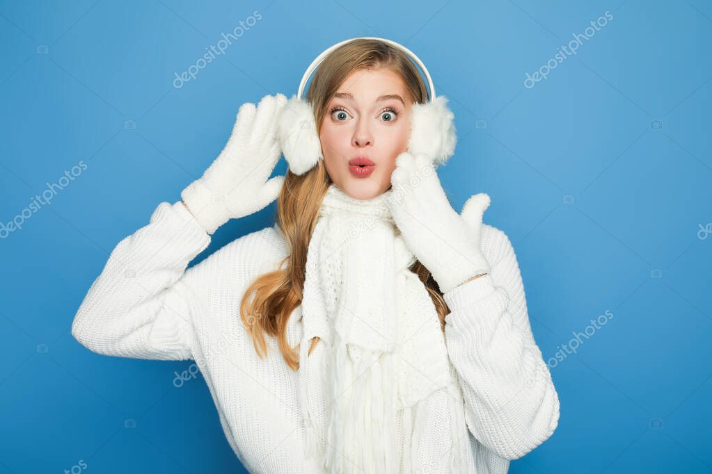 surprised beautiful woman in winter white outfit isolated on blue